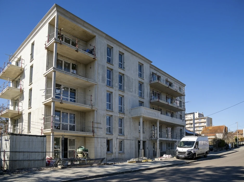 Chantier de construction d'un immeuble résidentiel R+4, façade en béton apparent non enduit, balcons en porte-à-faux, échafaudages tubulaires métalliques, garde-corps provisoires