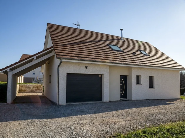 Chantier de construction extérieur avec maçon en salopette bleue et t-shirt rouge tenant une brique perforée et une truelle
