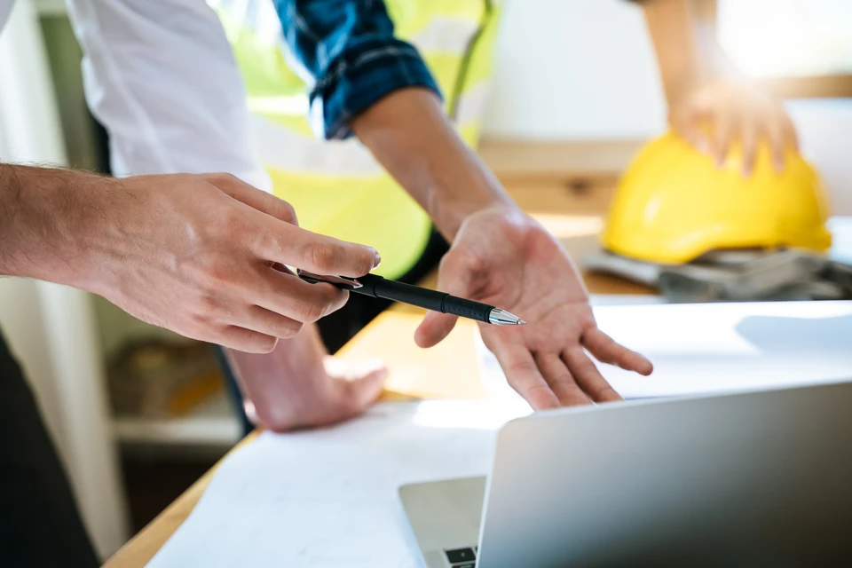 Chantier de construction extérieur avec deux professionnels du bâtiment consultant des plans architecturaux