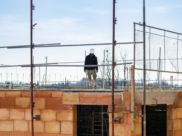 Un maçon en tenue de travail pose des blocs de béton cellulaire sur un chantier extérieur