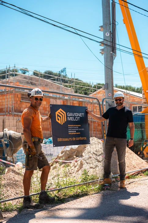 Ouvrier en équipement de sécurité avec casque jaune et gilet bleu supervise un chantier de rénovation intérieure