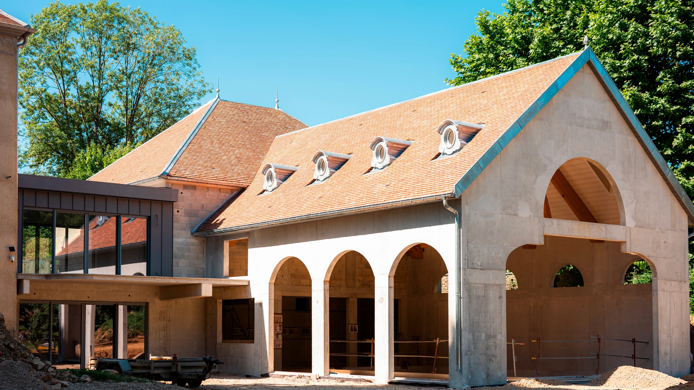 Château français en pierre calcaire avec façade classique à deux étages, tour cylindrique latérale, nombreuses fenêtres à volets verts, escalier extérieur à double révolution menant à l'entrée principale, jardin paysager au premier plan