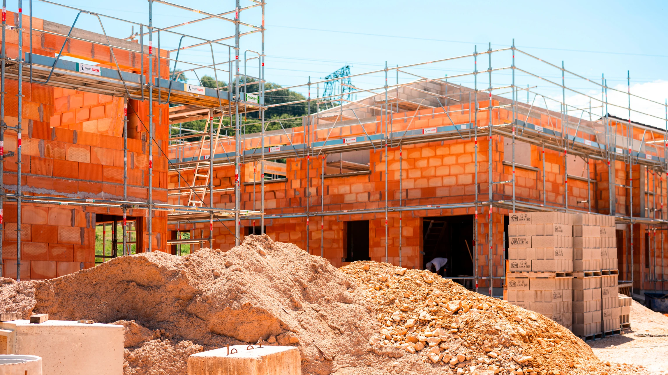 Un maçon en tenue de travail pose des blocs de béton cellulaire sur un chantier extérieur